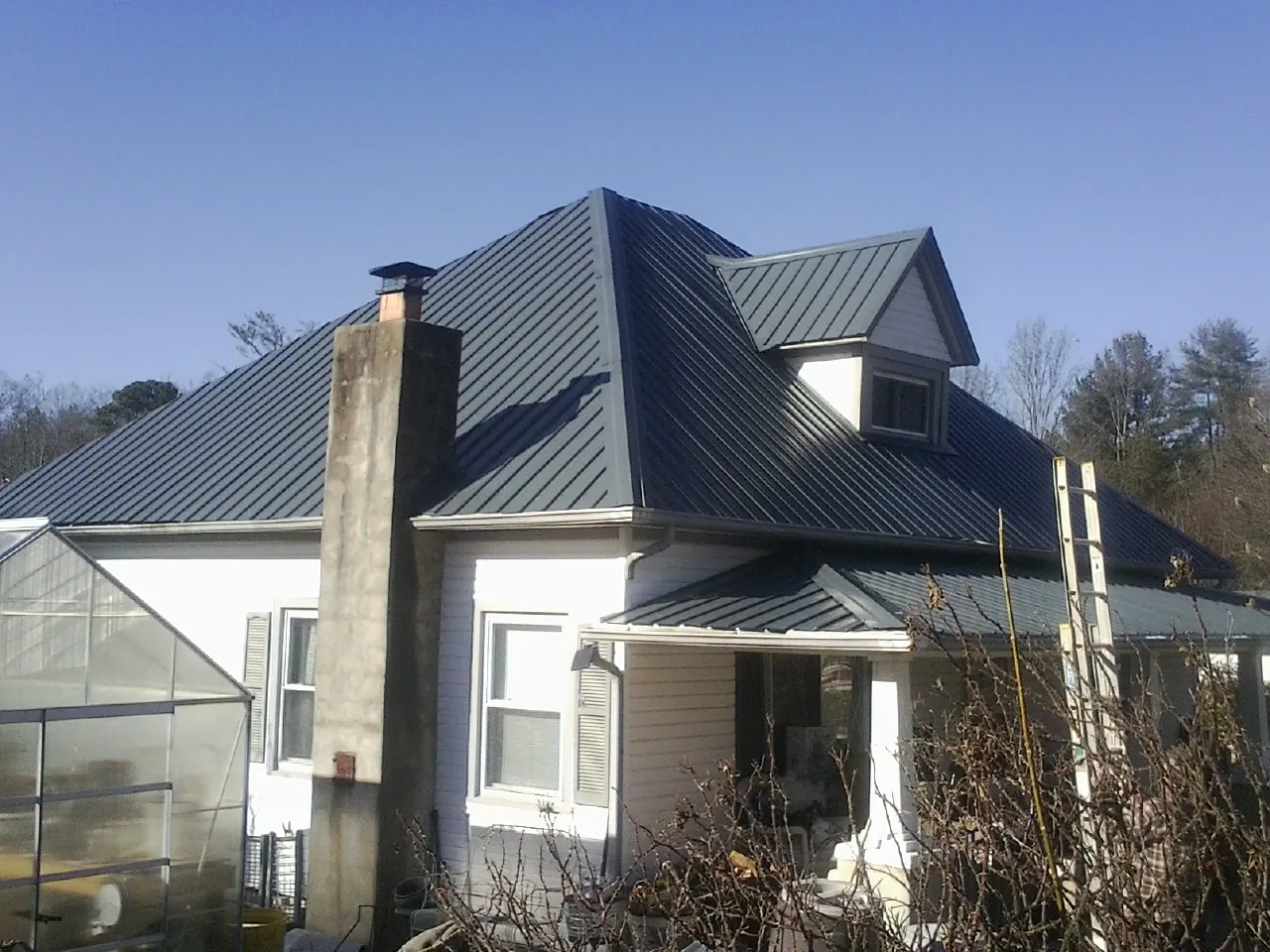 Dark blue standing seam metal roof on a white farmhouse with dormer — Slate & Tile Roof Repair by Roofing Brothers in Delphi