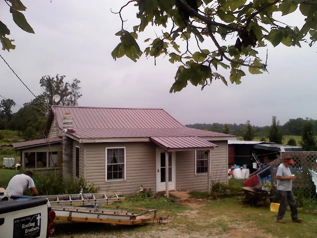 Crew finishing a mauve metal roof on a small farmhouse in Delphi