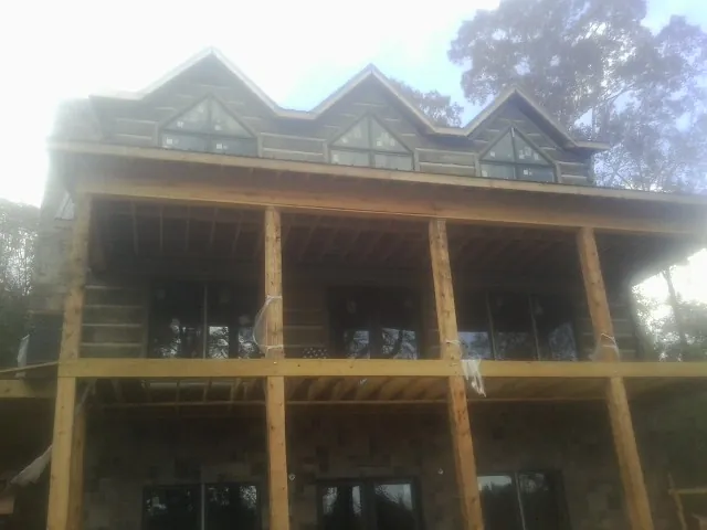 Dormers and porch framing on a large log home under construction — Roof Coating work by our crew in Delphi