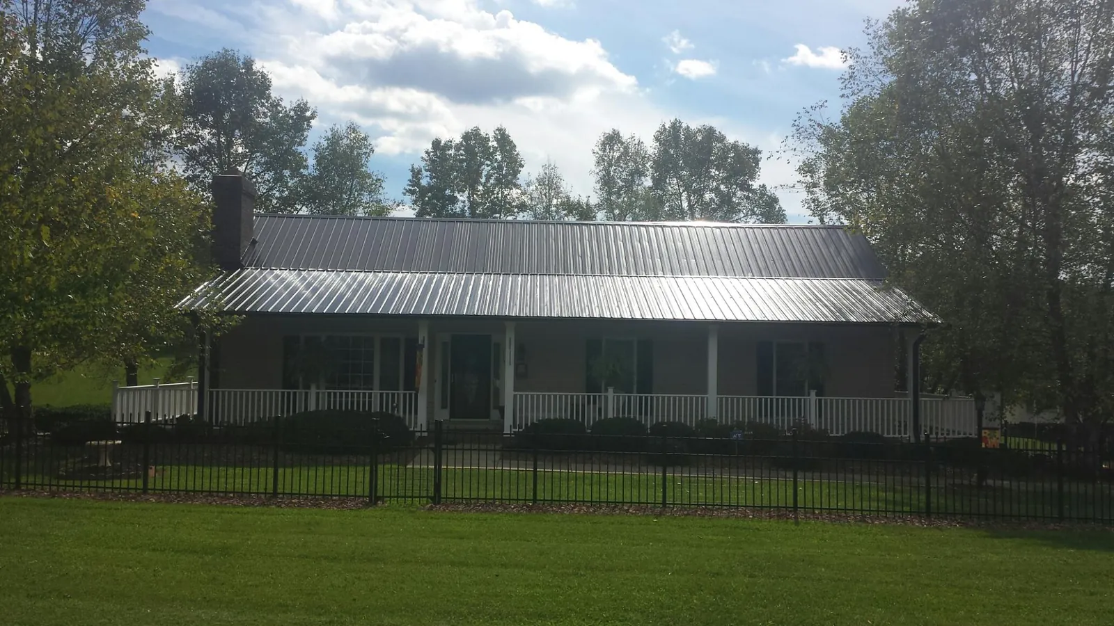 Gray metal roof on a brick ranch with a full width front porch — Gutter Guard Installation work by our crew in Delphi