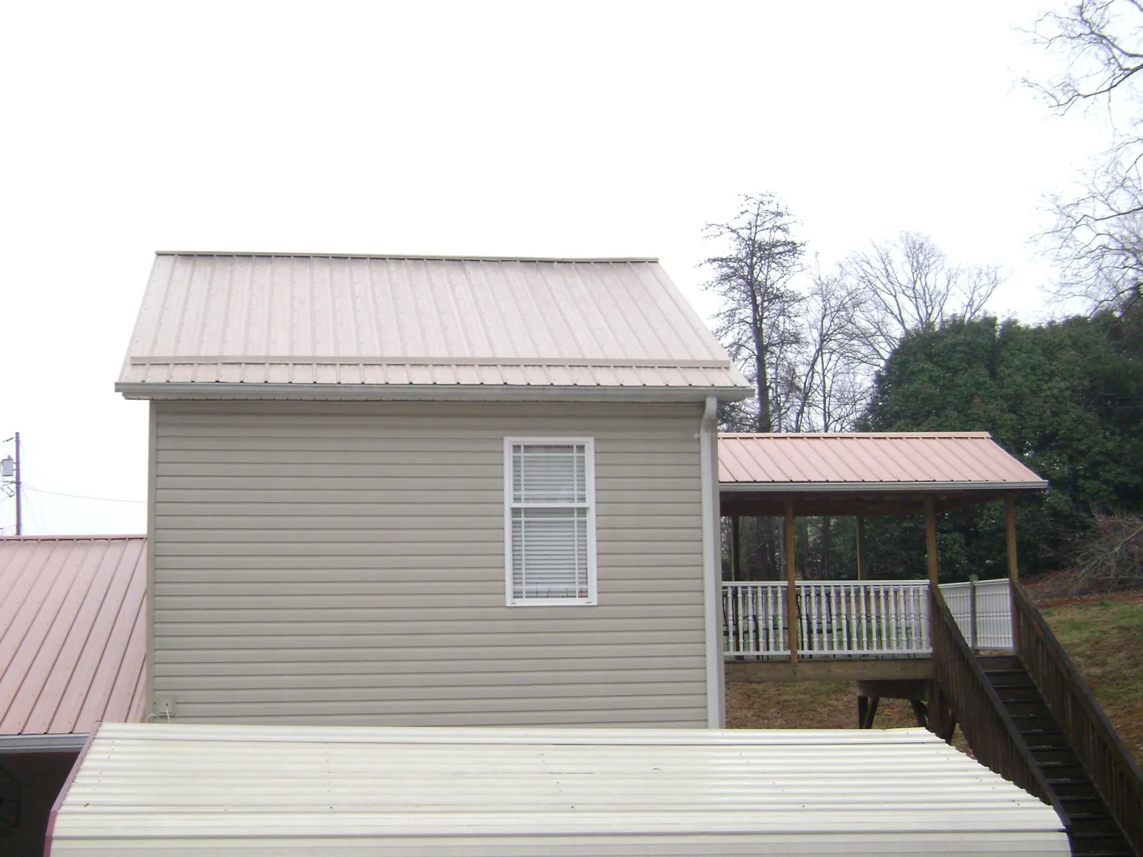 Tan metal roofs on a two story addition and attached porch, from a Roof Replacement job in Delphi