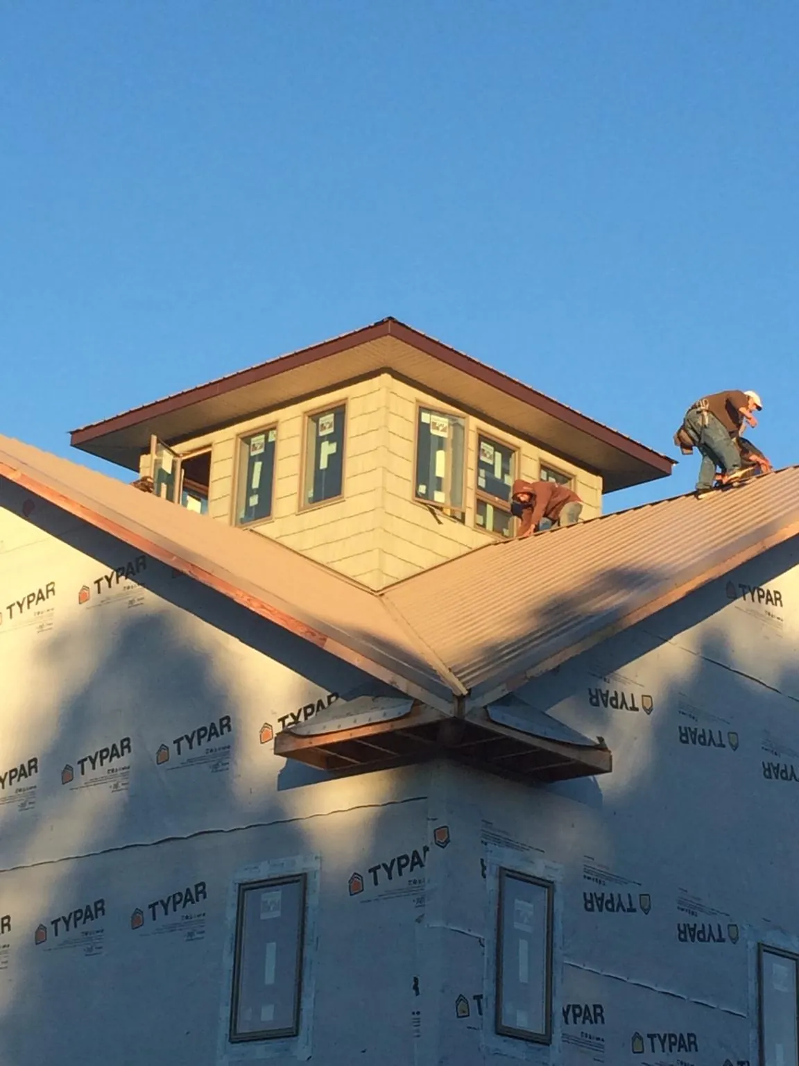 Roofers working around a rooftop cupola on a new metal roof at sunset — Roof Waterproofing in Delphi by Roofing Brothers